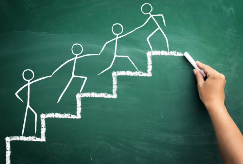 Chalkboard drawing of stick figures moving forward