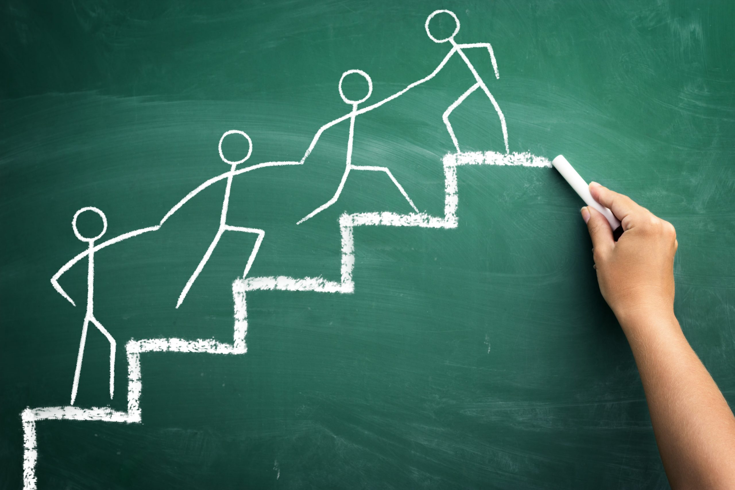 Chalkboard drawing of stick figures moving forward