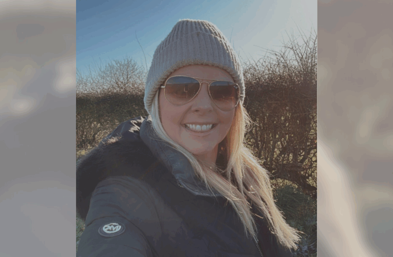 Blonde woman smiling in sunglasses and beanie hat.